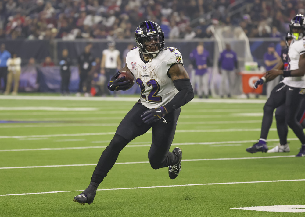 Derrick Henry, in white jersey and black pants, runs toward the sideline on the right side of the field.