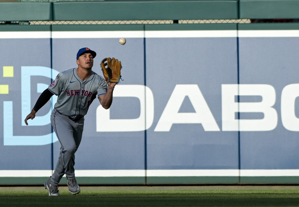 Tyrone Taylor comes in and is about to make a catch as he holds his glove up in his left hand.