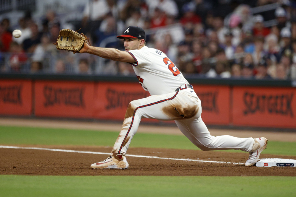 Matt Olson stretches towards third base as he holds out his glove awaiting a throw.