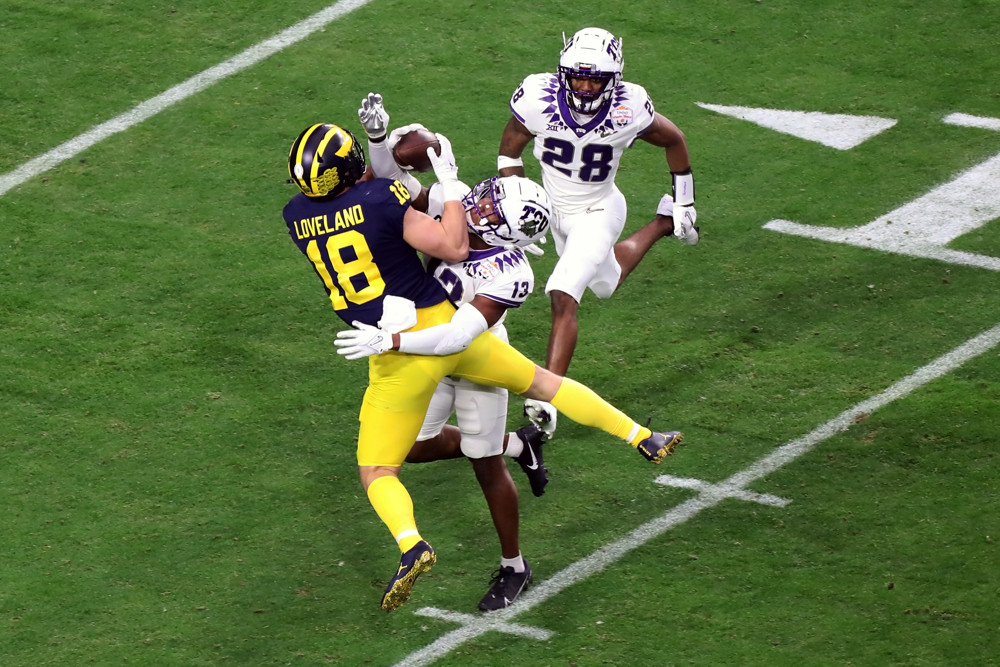 Colston Loveland makes a catch and falls to the turf with a TCU defender drapped on him.