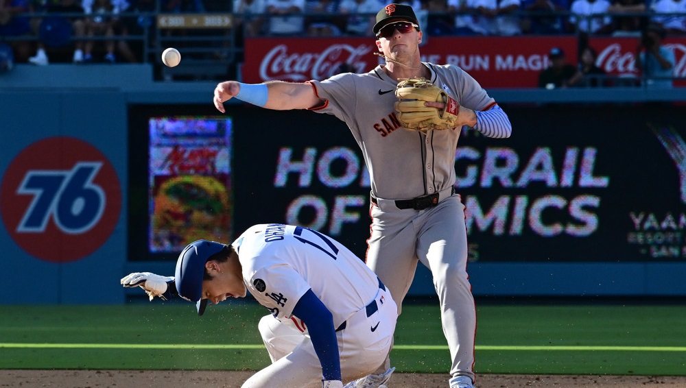 Giants second baseman Christian Koss throws to second base, just over Shohei Ohtani, who has slid into him and is ducking to avoid getting hit