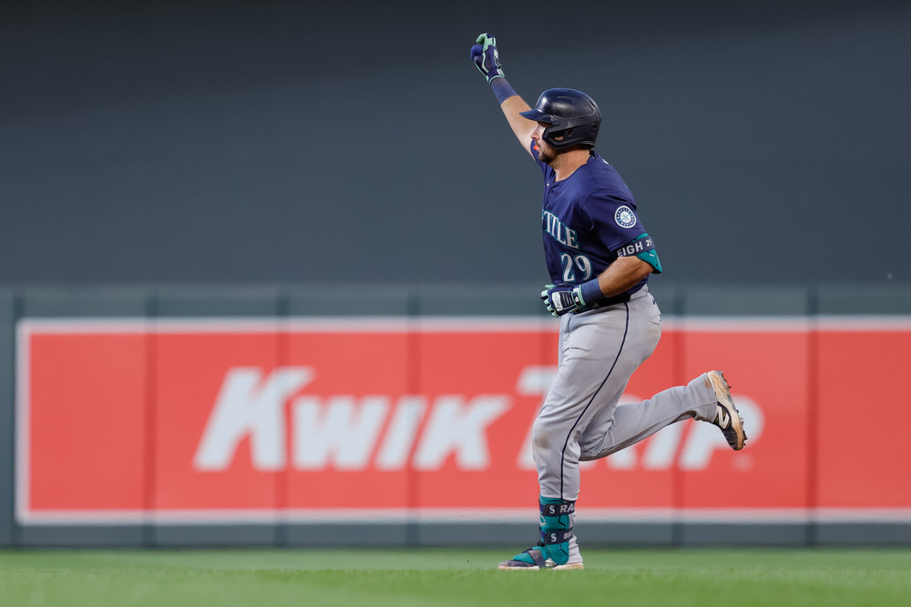 Cal Raleigh raises his right fist as he runs the bases to celebrate a home run.