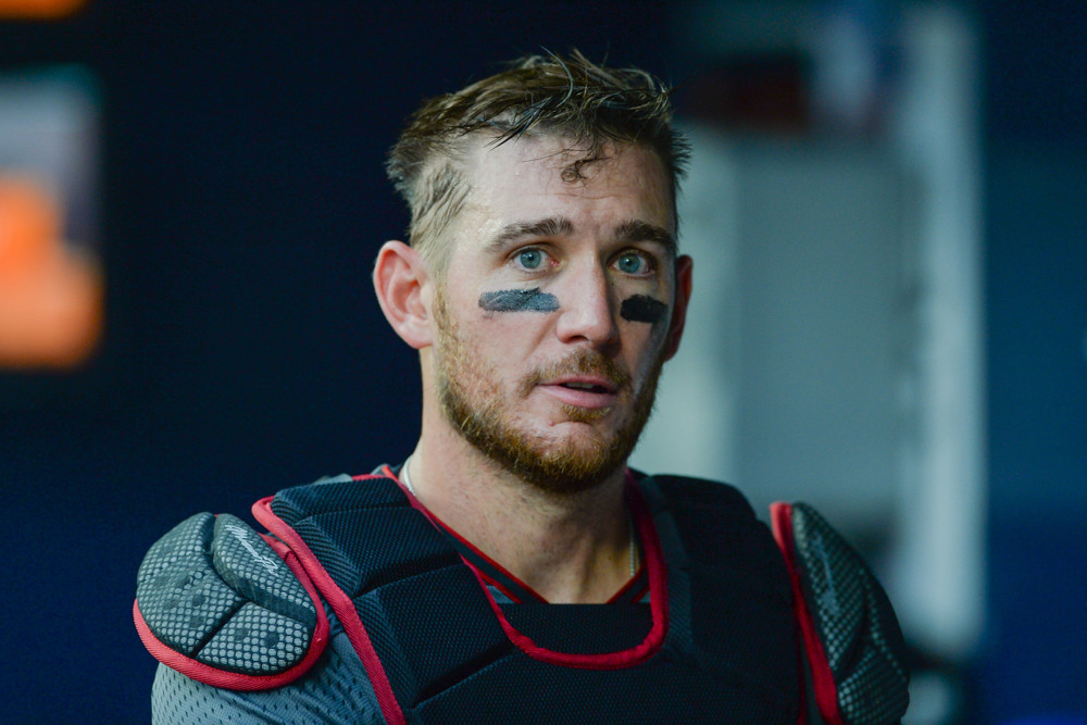 Jeff Mathis stands in the dugout with his chest protector on but his catcher's mask off