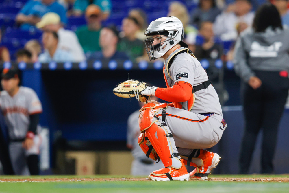 Patrick Bailey, squatting in his catching position, looks off to the side.