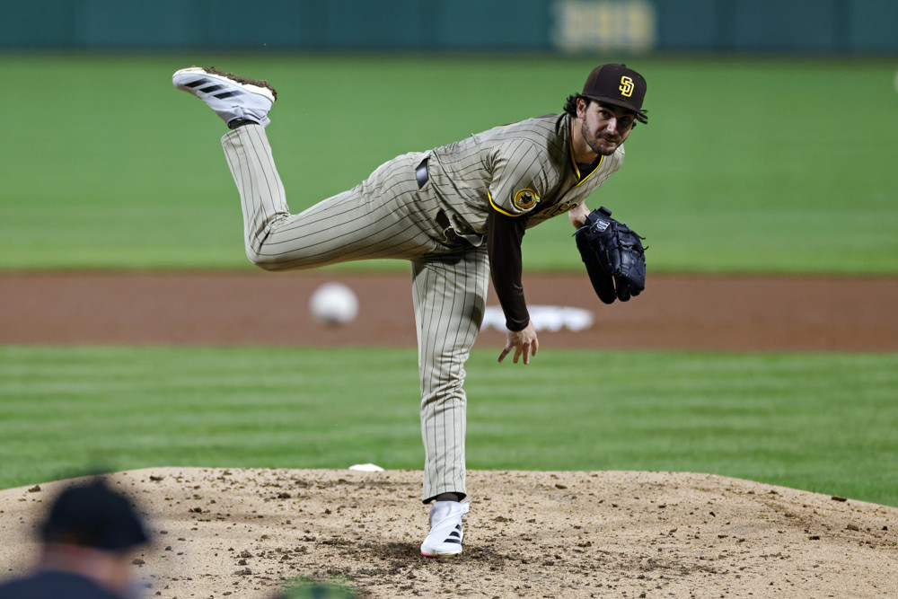Dylan Cease is in the middle of his follow through as he throws a pitch. He's wearing a grey uniform and a brown Padres cap.