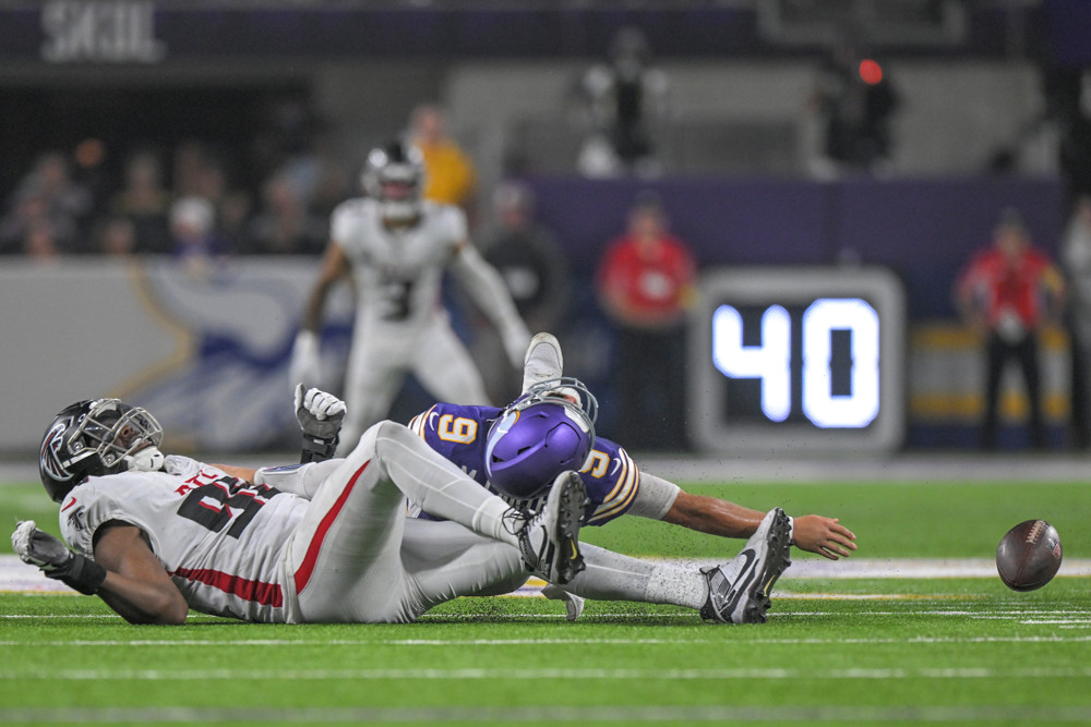 J.J. McCarthy lying on his back after getting sacked.
