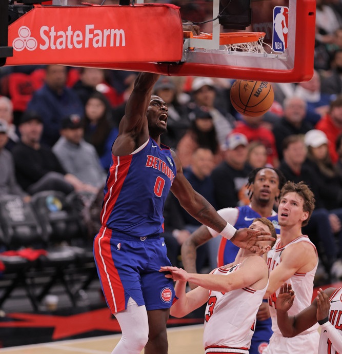 Jalen Duren, wearing a blue Pistons jersey with red No. 8, dunks with his right hand.