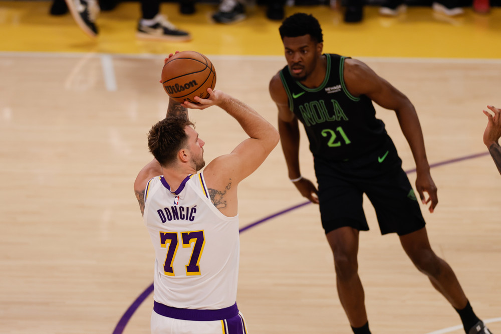 Luka Doncic (white jersey, # 77) shoots a jump shot as a defender watches in the background