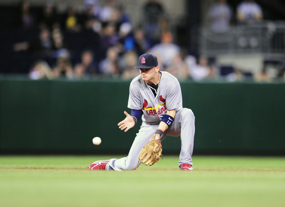 Brendan Ryan, in grey pants and a grey uniform top, goes to one knee (right knee down)to field a ground ball at shortstop.