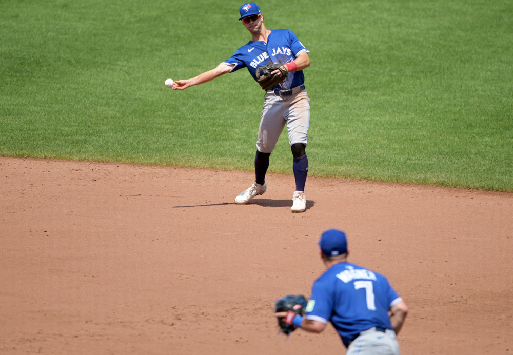 Ernie Clement, wearing a Blue Blue Jays jersey and grey baseball pants, makes a sidearm throw to first base.