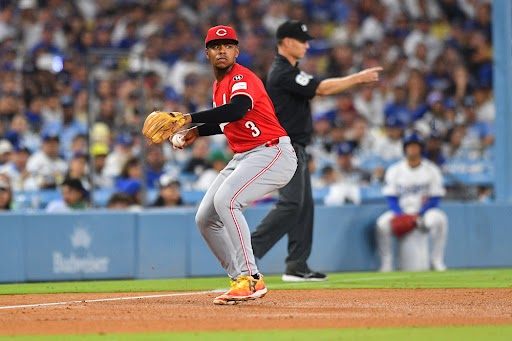 KeBryan Hayes, wearing greay pants and a red Cincinnati Reds jersey with a red 'C' cap prepares to make a throw from third base to first base.