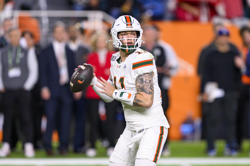 Carson Beck, wearing an all-white Miami Hurricanes uniform and a white helmet, prepares to throw a football.