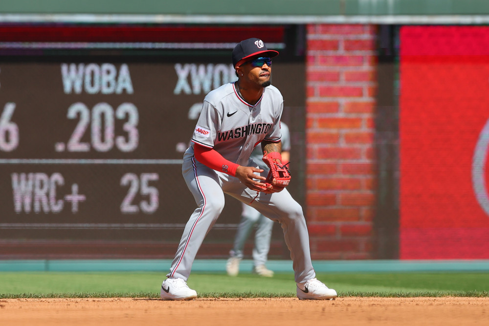 Nasim Nunez, a 5-foot-8 second baseman for the Washington Nationals, crouches in a ready position as he waits for a ball to be hit. He's wearing a grey Nationals jersey and a dark blue baseball cap.