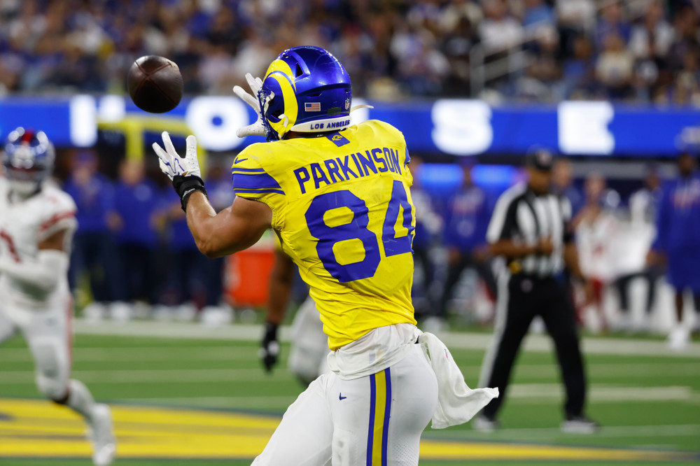 Colby Parkinson of the Rams, in yellow jersey with blue #84 lettering, is about to make a catch, shoulder-high.